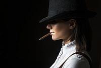 Lewy profil kobiety w staromodnej bluzce i kapeluszu z cygarem w ustach