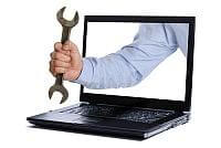 Ręka wyciągająca z laptopa klucz francuski
