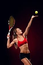 Kobieta z rakietką tenisową w dłoni i piłka tenisowa w powietrzu.