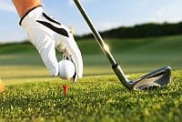 Ręka golfisty stawia piłeczkę na podstawce w trawiastym plenerze