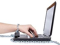 Ręka przywiązana łańcuchem i kłódką do laptopa