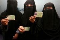 Trzy stojące muzułmanki pokazują przed sobą swoje dowody osobiste