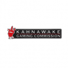 Czerwona głowa Indianina i biały napis KAHNAWAKE GAMING COMMISSION na ciemnoszarym tle i całość na białym tle
