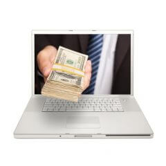 Ręka biznesmana wystaje z ekranu laptopa oferując dolary