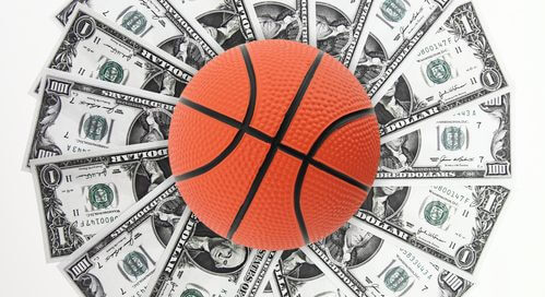 Piłka do koszykówki leży na wachlarzu z dolarów