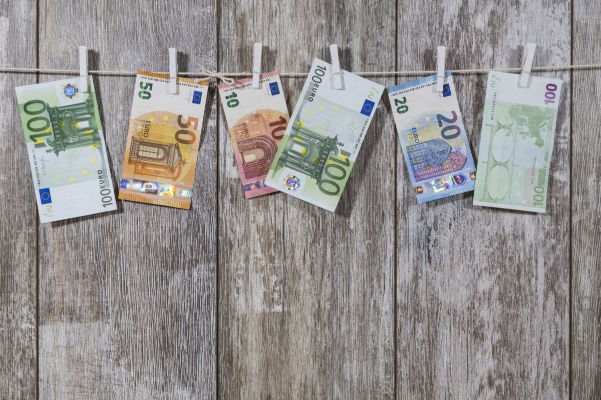 Banknoty 10 20 50 i 100 euro powieszone spinaczami na sznurku na tle drewnianych desek