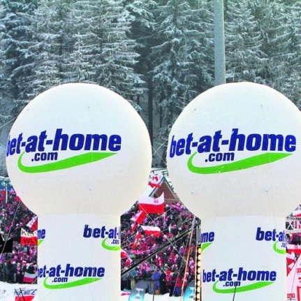 Dwa duże balony z logiem bukmachera bet-at-home na tle trybun i lasu