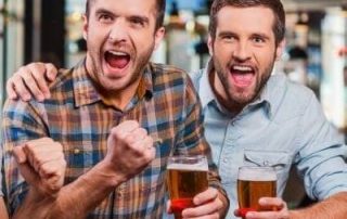 Uradowani kumple w barze z piwem w ręce