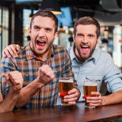 Uradowani kumple w barze z piwem w ręce