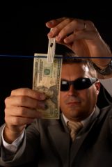 Mężczyzna w garniturze i ciemnych okularach wiesza na sznurku banknot dolarowy