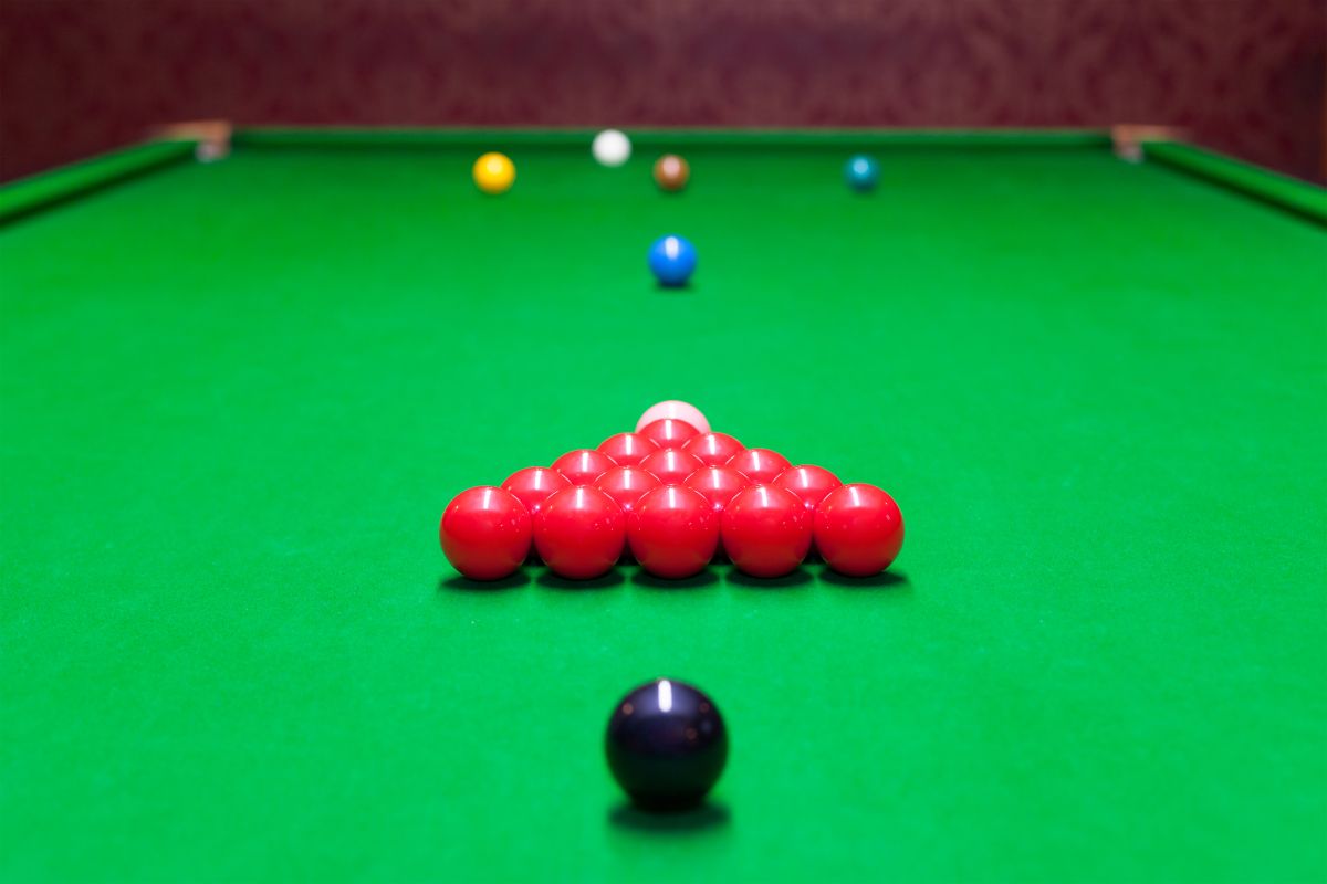 Czarna bila ustawiona za trójkątem czerwonych kul na stole do snookera