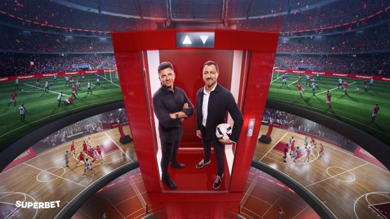 Mateusz Borek i Jerzy Dudek w czerwonej windzie na tle półokrągłego stadionu piłkarskiego