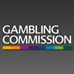 Biały napis GAMBLING COMMISSION z kolorowym paskiem jako podkreślenie na ciemno szarym tle
