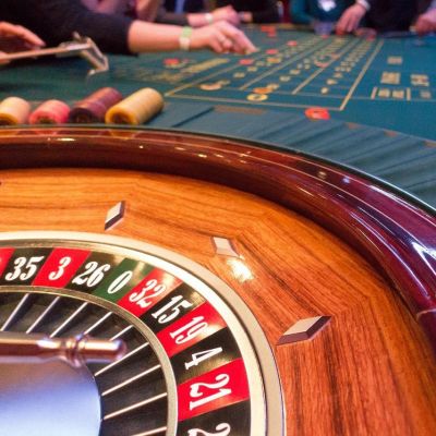 Widok ćwiartki ruletki z zielonym stołem kasyna i rękami grających w tle