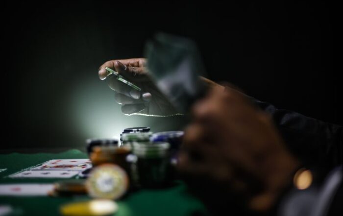 Podświetlona ręka trzyma żetony na zielonym stole z żetonami