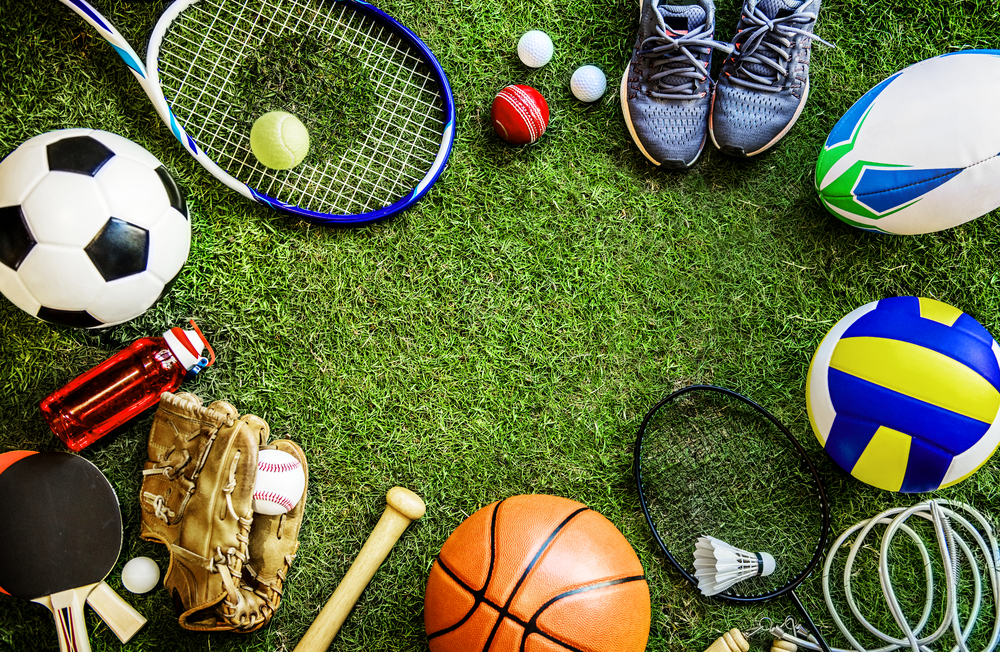 Akcesoria różnych dyscyplin sportowych rozłożone w pierścień na zielonej trawie