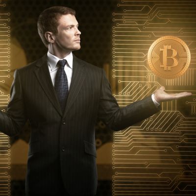 Mężczyzna w garniturze w pozycji wagi na czarno złotym tle podtrzymuje lewą ręką złotą monetę Bitcoin